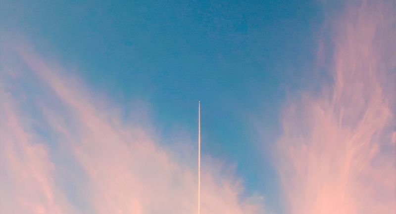 raket schiet omhoog in blauwe lucht met roze wolken want afstand speelt geen rol